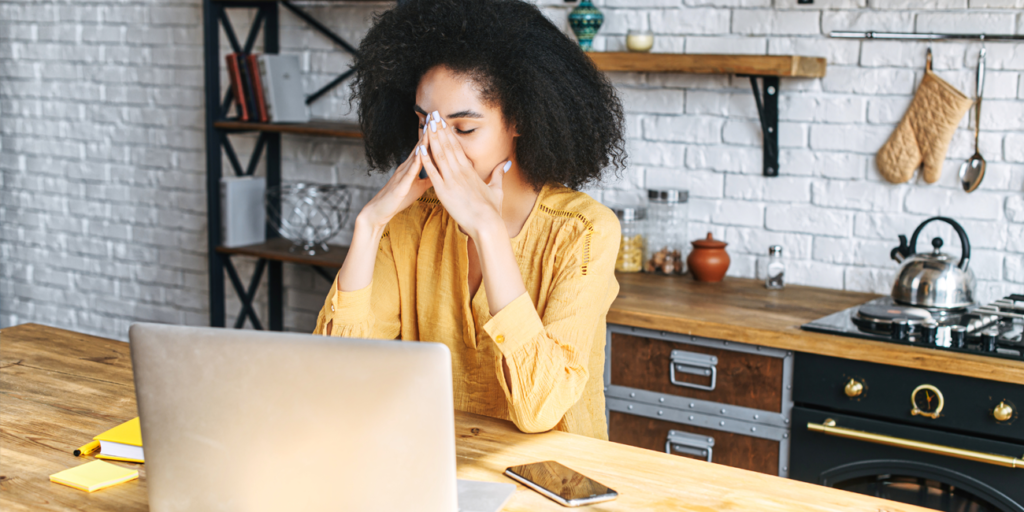 A young woman is tired from remote work with laptop